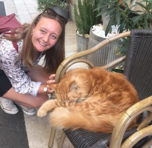 Picture of Indea. A young woman smiling as she stroked a large ginger cat