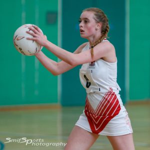 A photo of Lizzie playing netball, poised to throw the ball