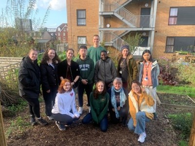 A photo of volunteers outside in an allotment, standing together and smiling
