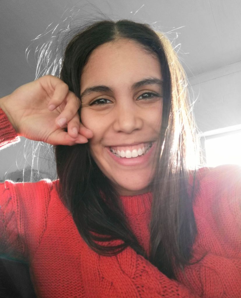 Isabella Cupido smiling widely. She is wearing a red jumper.