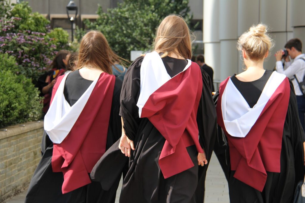 A photo of the backs of three Bristol graduates in their graduation gowns.