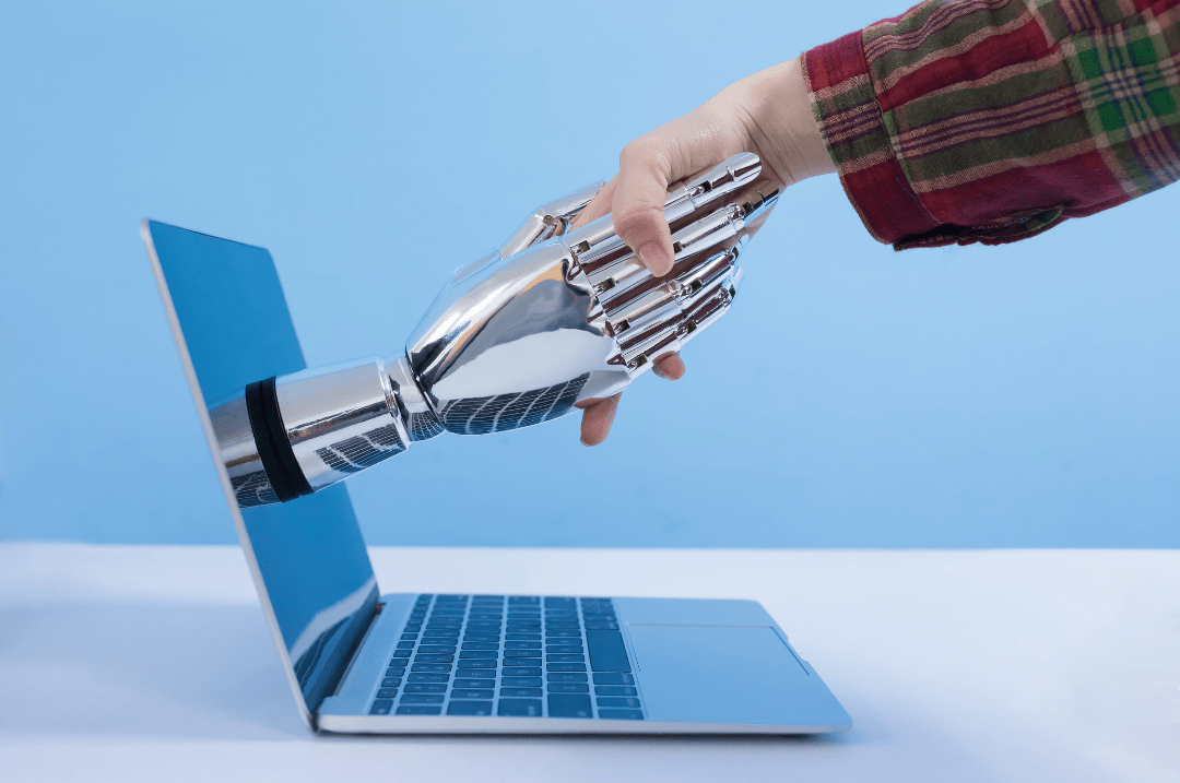 Image showing a robotic hand coming out of a laptop, and shaking hands with a human hand