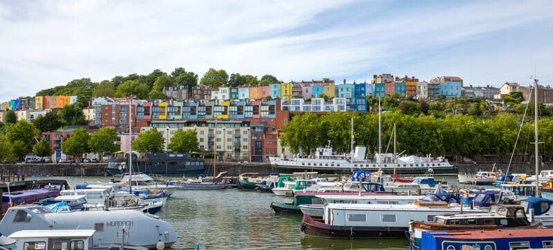 A view across Bristol harbourside, including houseboats and multi-coloured houses  
