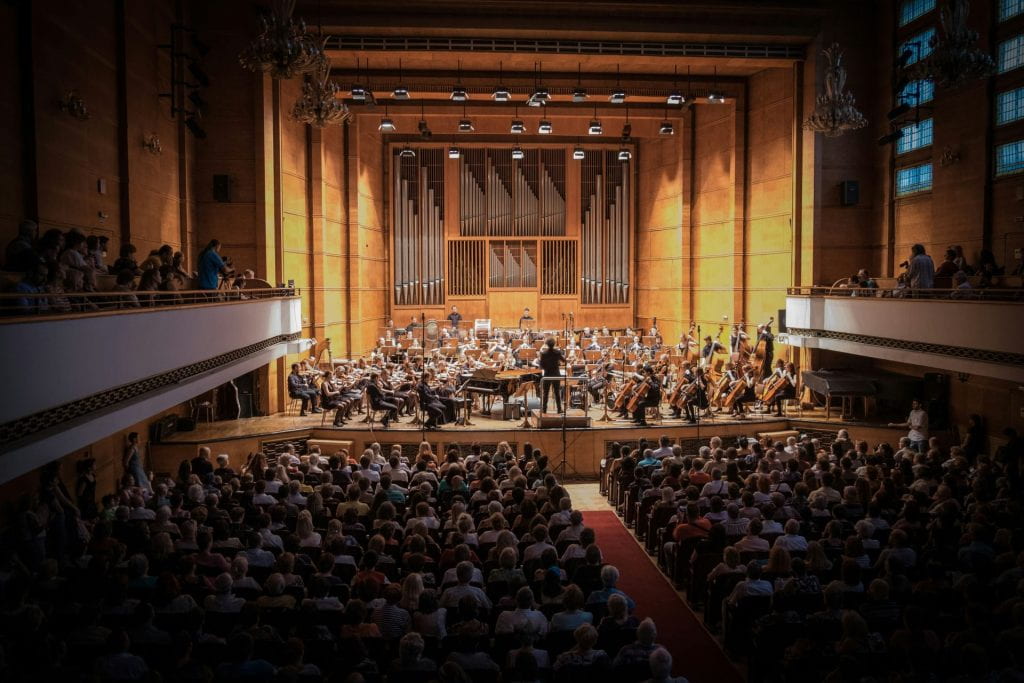A photo of the inside of a concert hall with an orchestra performing