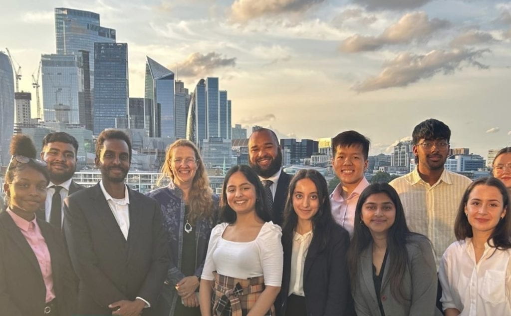 Image of Elena and her fellow Patchwork Masterclass cohort of students together with a backdrop of the city of London skyline.