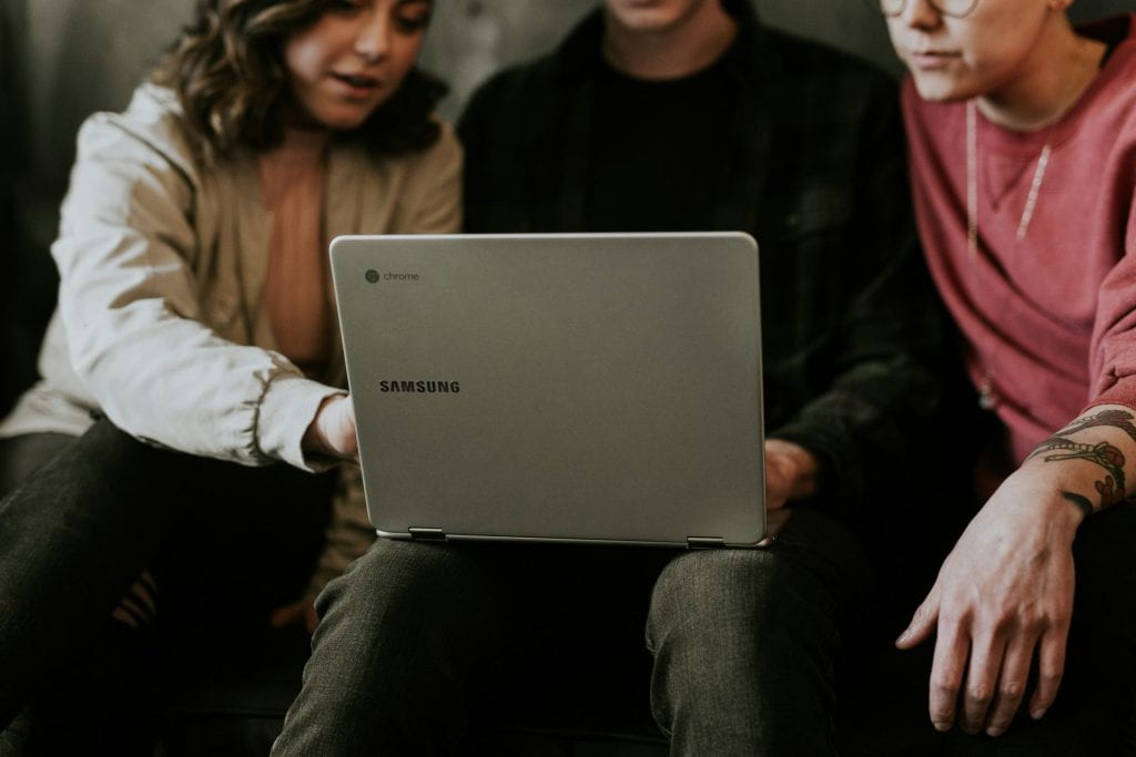 Three students reviewing something on a laptop.